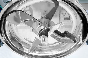 particolare di macchinario con lame rotanti in acciaio inox per la miscelazione delle materie...