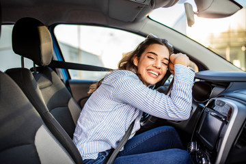 Young and cheerful woman enjoying new car hugging steering wheel sitting inside. Woman driving a new car. Woman Driver Portrait at Car - Powered by Adobe