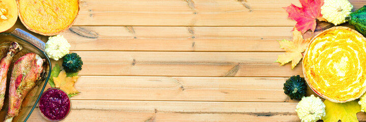 Festive wooden table with turkey drumsticks, pumpkin pies and maple leaves. Happy thanksgiving day background