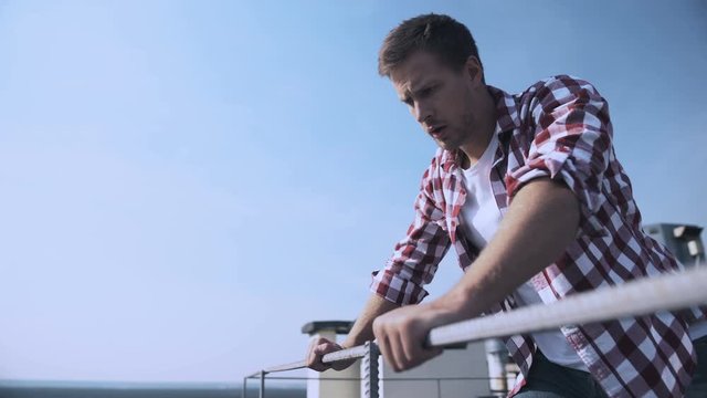 Scared male looking down standing rooftop, fear of heights, problem hopelessness