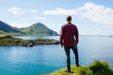 Fototapeta premium A men enjoy the scenic nature. Northern beauty panoramic view. Fjord, ocean and mountain landscape. Travel, adventure. Sense of freedom, relax lifestyle. Explore North Norway. Summer in Scandinavia