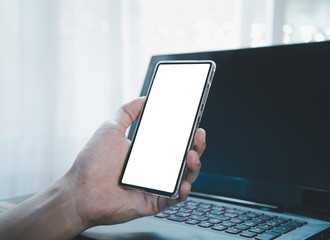 Men hand holding smartphone blank white screen white laptop. Mobile payments, scan code concept.
