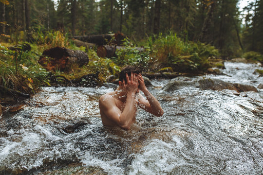 young nude man washing his face while standing in the river, close up photo. lifestyle, free time. spare time