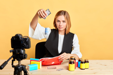 Famous female nutritionist drops down blister pack with pills and drugs, takes part in advertisement photoshoot, promotion project of pharma company. Marketing and healthcare concept.