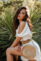 beautiful woman with dark hair in elegant dress posing in summer garden