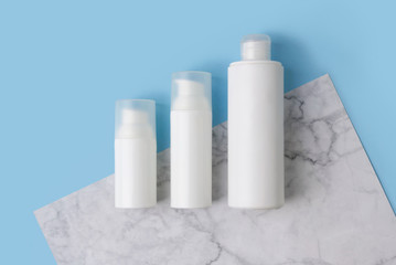 Minimal composition with cosmetic bottles on creative blue and marble background