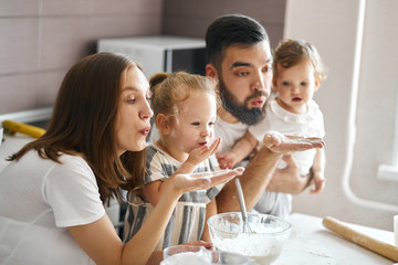 young funny family blowing flour in the kitchen, sending kiss, close up side view photo. entertainmnet concept, lifestyle