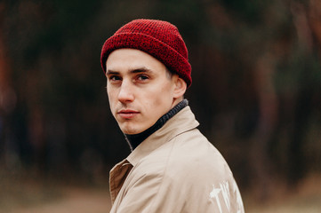 A close-up portrait of a tourist guy. A traveler in a red knitted hat turns back.