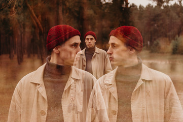 Multiple exposure. Traveler in a raincoat and a red knitted hat. Loneliness. Psychology