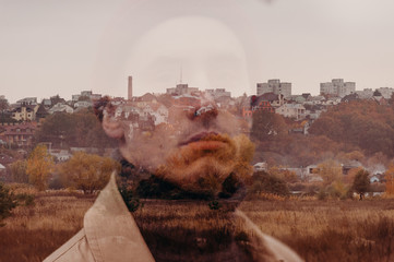 Multiple exposure. Traveler in a raincoat and a red knitted hat. Loneliness. Psychology