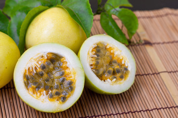 There are yellow Passion fruits with green leaves on wooden table background.