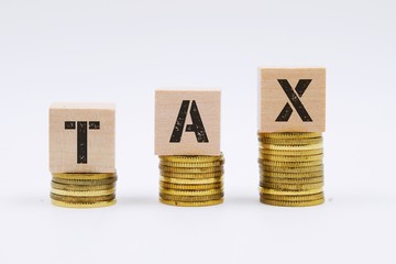 Tax concept with wooden block on stacked coin