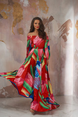 Young beautiful pretty woman in colorful red summer dress posing against wall. Studio full length...