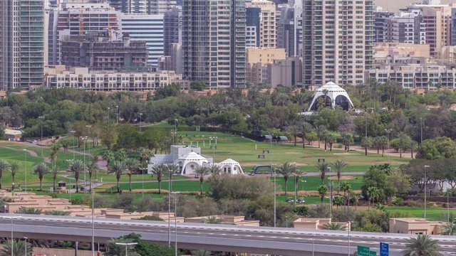 Dubai Golf Course with a cityscape of Gereens and tecom districts at the background aerial timelapse. Traffic on sheikh zayed road with junction