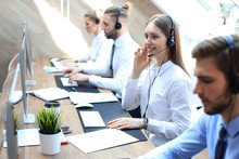 Female customer support operator with headset and smiling accompanied by her team.