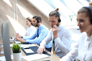 Portrait of call center worker accompanied by his team. Smiling customer support operator at work.