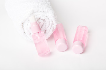 Three  bottles of tonic or lotion sprinkled with water on pink or powder background. Freshness and body care. Female cosmetics. Micellar water. Travel set of face care cosmetic