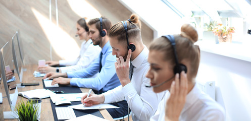 Portrait of call center worker accompanied by his team. Smiling customer support operator at work.