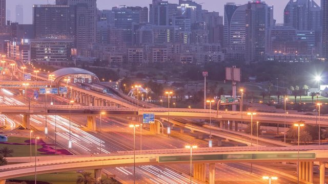 Dubai Golf Course with a cityscape of Gereens and tecom districts at the background aerial night to day transition timelapse. Traffic on sheikh zayed road with junction