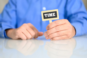 Geschäftsmann mit einer kleiner Tafel auf der TIME steht