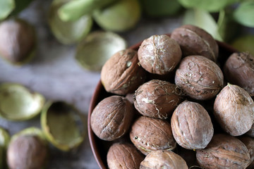 Inshell walnuts in a bowl. Harvest walnuts. The leaves of the walnut tree. Walnuts in a green peel. Selective focus. Macro.