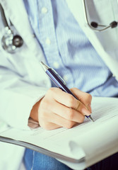 Female doctor hand hold silver pen filling patient history list at clipboard pad. Panacea and life save, prescribing treatment.
