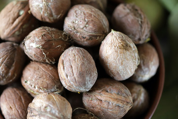 Inshell walnuts in a bowl. Harvest walnuts. The leaves of the walnut tree. Walnuts in a green peel. Selective focus. Macro.