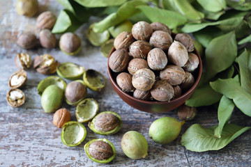 Inshell walnuts in a bowl. Harvest walnuts. The leaves of the walnut tree. Walnuts in a green peel. Selective focus. Macro.