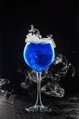 Blue cocktail, smoke effect, black background. Dry ice smoke