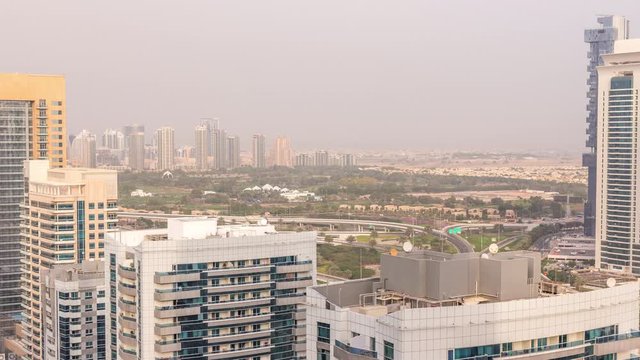 Dubai Marina towers with Golf Course and cityscape of Gereens and tecom districts at the background aerial timelapse. Traffic on road with junction