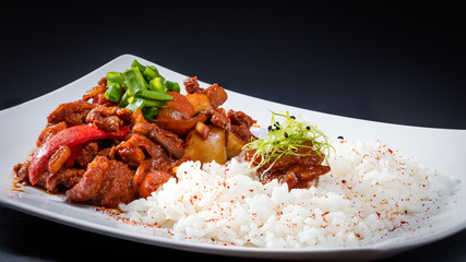 meat with rice and vegetables on a black background