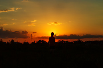 Fototapeta na wymiar Silhouette of a boy against the backdrop of the dawn sun