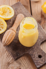 Lemon curd in a glass jar on a wooden background, ingredients for cooking, lemon kyrd recipe