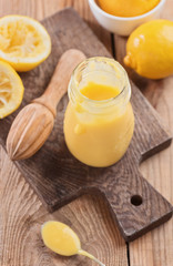 Lemon curd in a glass jar on a wooden background, ingredients for cooking, lemon kyrd recipe