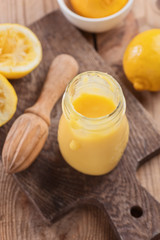 Obraz na płótnie Canvas Lemon curd in a glass jar on a wooden background, ingredients for cooking, lemon kyrd recipe