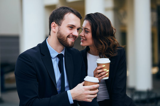 cheerful smiling pleasant woman and man in elegant fashion suits rejoicing at free time outdoors, warm feeling, emotion , man and woman fall in love. I love you,woman whispering something to boyfriend