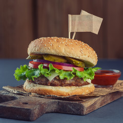 Burger with a meatball and fries with two flags on a wooden cutting board