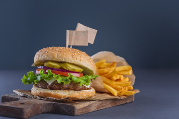 Two flags in burger with a meatball and fries on a wooden cutting board