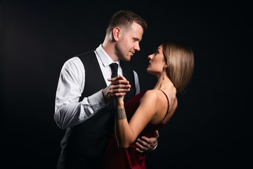 Beautiful young loving couple dancing tango Emotions, love.close up side view photo. isolated black...
