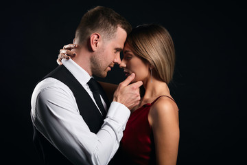 sexy young elegant couple in the tender passion, close up side view photo. isolated black background, studio shot. romance, desire