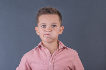 dissatisfied school-age boy in peach shirt