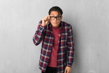 Man over grunge wall with glasses and surprised