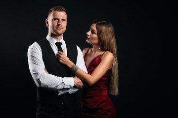 fashion blonde woman with long straight hair helping her man to prepare for event. close up portrait, isolated black bckground, studio shot. copy space