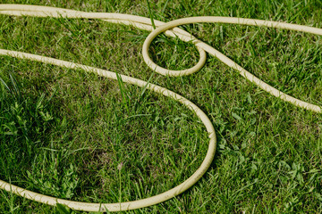 Yellow flexible hose lying on  green grass