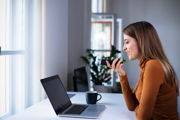 Young woman office worker using voice recognition on the phone