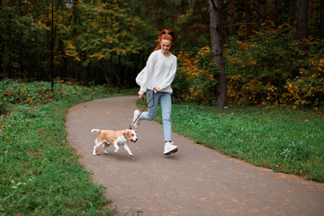 positive young woman in white sweater, jeans jogging with her pet. full length photo.spare time, pastime, full lenegth photo. health care