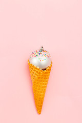 Christmas sweet ball in waffle cone on pink background. Vertical photo. Flat lay