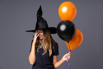 Young witch holding black and orange air balloons laughing