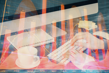 Multi exposure of graph with man typing on computer in office on background. Concept of hard work.