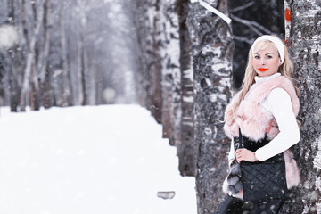 Snowy day blonde girl on a walk in a winter park